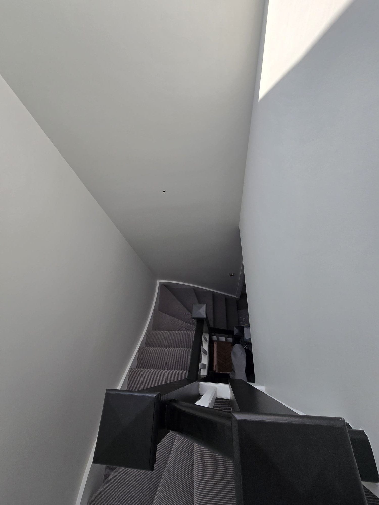 Tall stairwell finished in a pale neutral paint with crisp corners and clean ceiling lines.